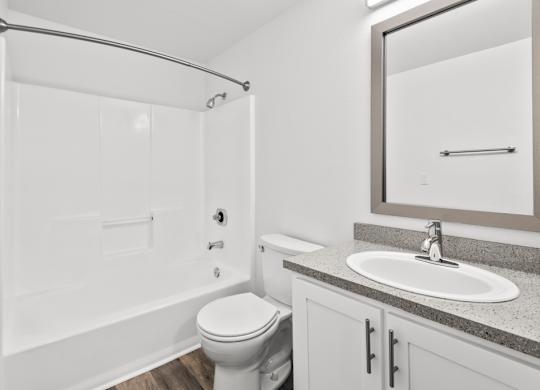 A white bathroom with a toilet, sink, and shower.