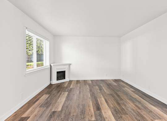 A room with a fireplace and wood flooring.