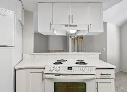 A white kitchen with a stove top oven and a refrigerator.