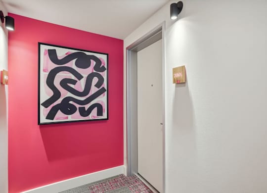 A hallway with a pink wall and a painting on it.