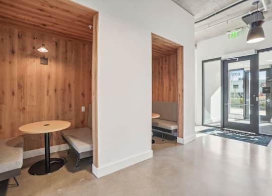 A room with a wooden wall and a white pillar with a round table and two chairs.