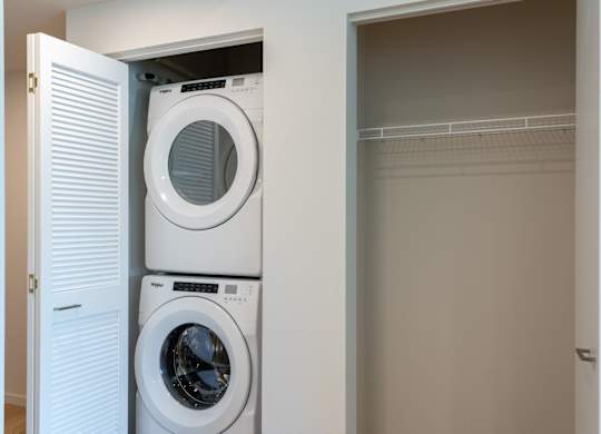 A white washing machine is in a cabinet under a white door.