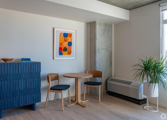 A blue cabinet sits next to a table with two chairs and a potted plant.