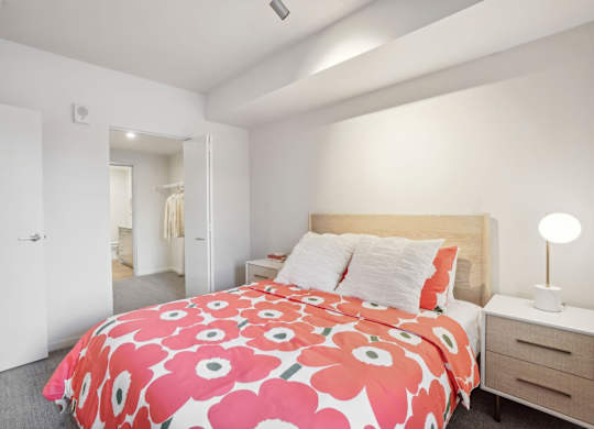 A bedroom with a bed, nightstand, and lamp.