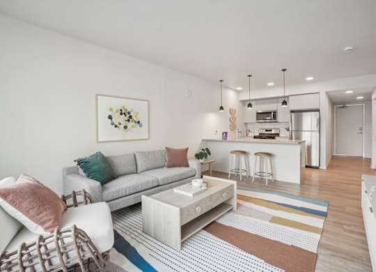A modern living room with a grey sofa, a coffee table, and a bar area in the background.
