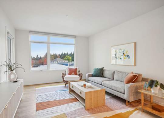 A living room with a grey couch, a coffee table, and a painting on the wall.