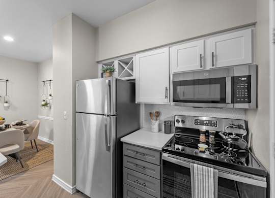 A modern kitchen with a refrigerator, microwave, and oven.
