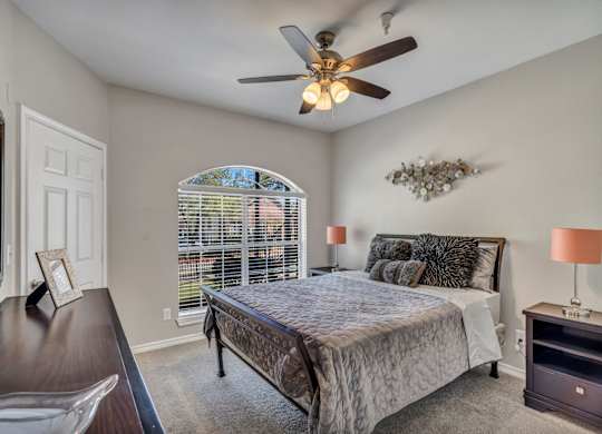 A bedroom with a bed, nightstand, and a ceiling fan.