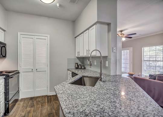 A kitchen with a granite countertop and white cabinets.