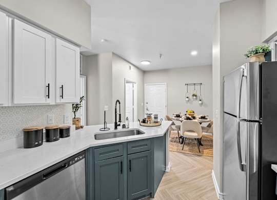A kitchen with a black refrigerator and a dining table with chairs.