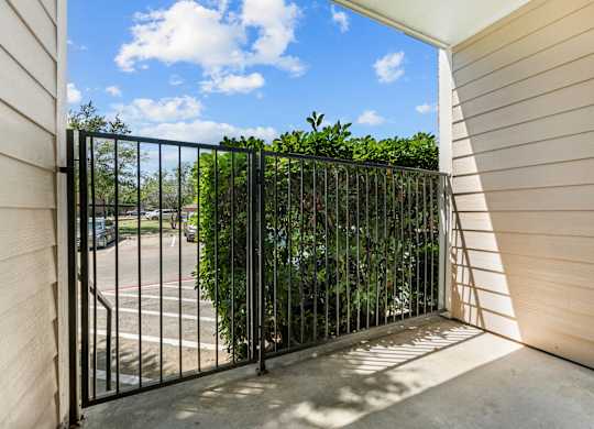 A black metal gate leads to a concrete patio.