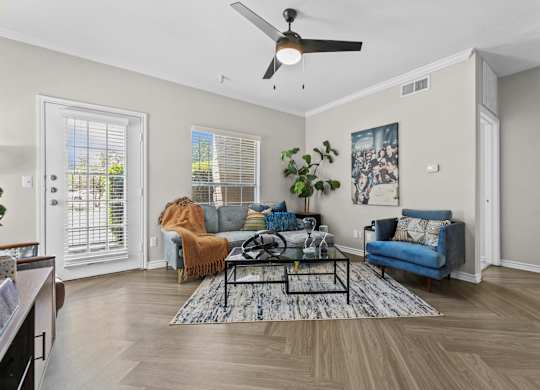 A living room with a blue couch and a rug.