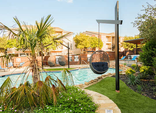 A pool area with a hanging chair and a cross-shaped sign.