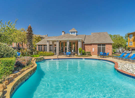 A swimming pool in a backyard with a house and lawn chairs.