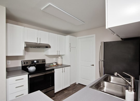 A kitchen with white cabinets and a black stove top.