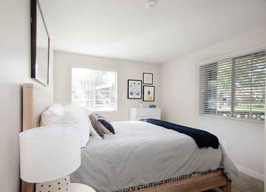 A bedroom with a bed, nightstand, and pictures on the wall.