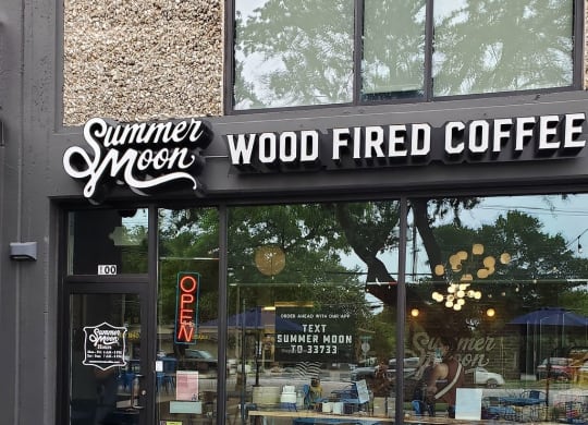 the outside of a coffee shop with blue tables and chairs