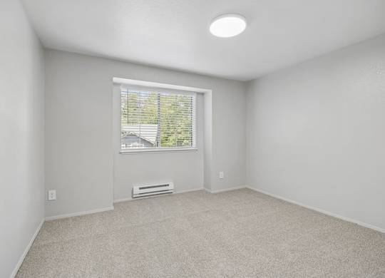 A room with a window and a radiator on the floor.