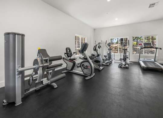 A spacious gym with a variety of equipment including treadmills, stationary bikes, and weight machines.