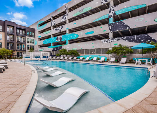 a swimming pool with lounge chairs and a building in the background