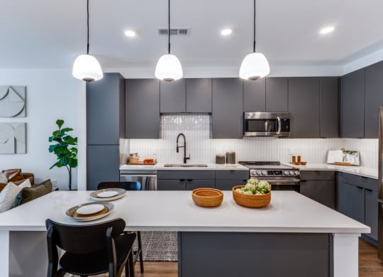 an open kitchen with a large white island and dark cabinets
