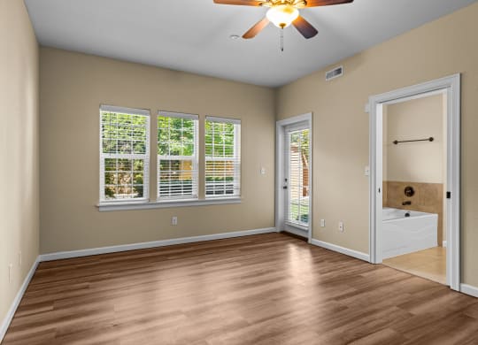 Little Tuscany Apartments & Townhomes - Bedroom with Bathroom, vinyl wood plank flooring, white woodwork, ceiling fan, natural light