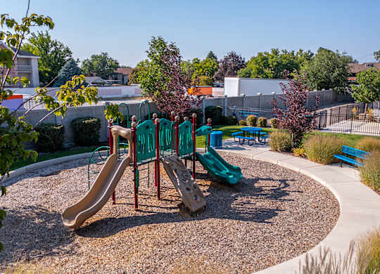 A playground with a green slide and a red slide.