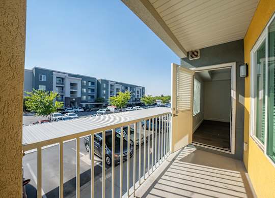 A balcony with a view of a parking lot and apartment buildings.
