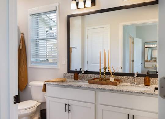 A bathroom with a toilet, sink, and mirror.