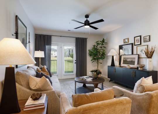 A living room with a beige couch, a coffee table, and a ceiling fan.