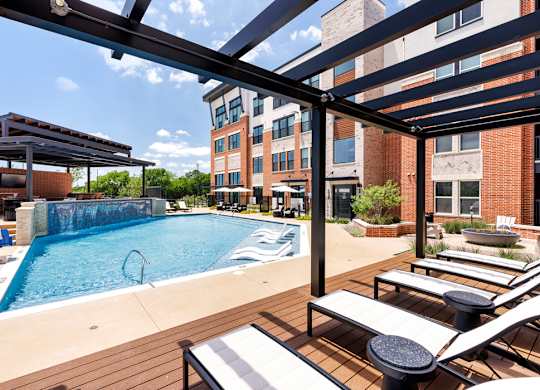 A pool with a slide and sun loungers.