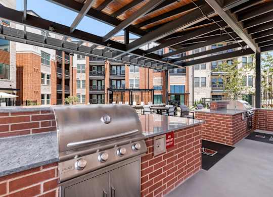 A patio with a grill and a brick wall.