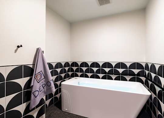A white bathtub sits in a bathroom with black and white tiles.