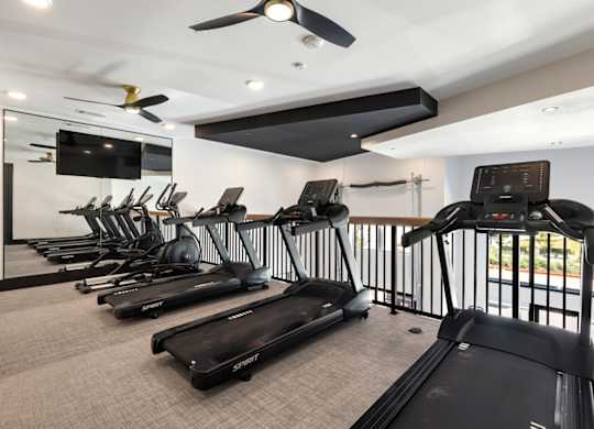 A gym with treadmills and a television.