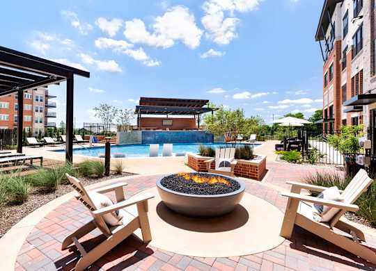 A patio with a fire pit and chairs.