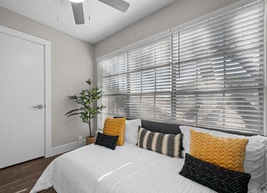 A bedroom with a bed, pillows, and a plant.