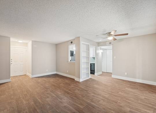 A room with a ceiling fan and wooden flooring.