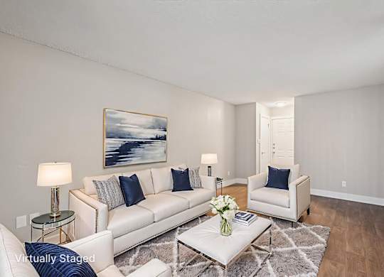 A living room with a white couch, a coffee table, and a painting on the wall.