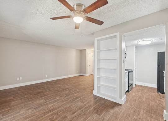A room with a ceiling fan and wooden flooring.
