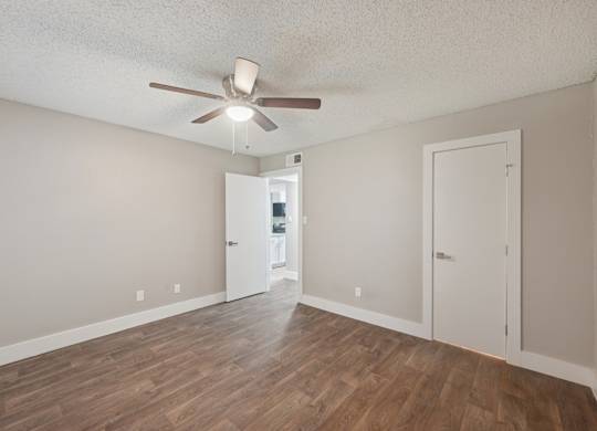 A room with a ceiling fan and wooden flooring.