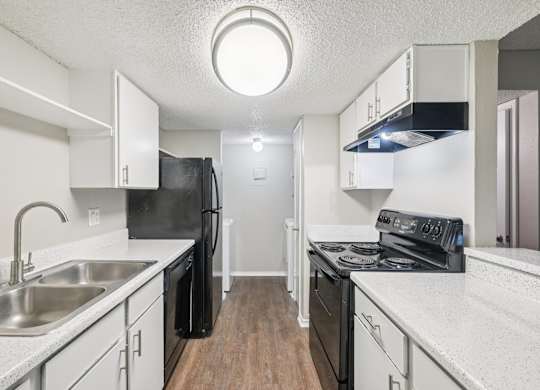 A kitchen with black appliances and white countertops.