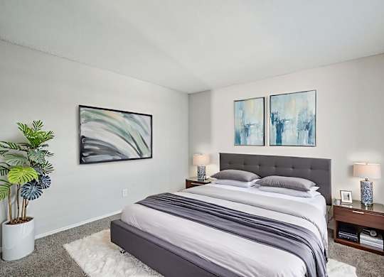 A bedroom with a large bed and two framed artworks on the wall.