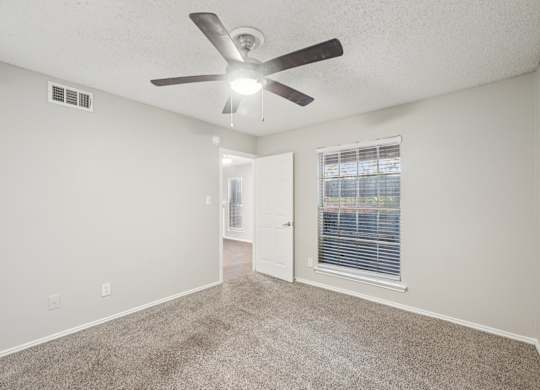 A room with a ceiling fan and carpeted floor.