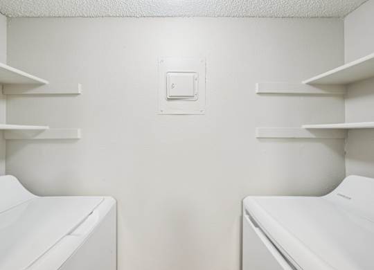 Two white washing machines in a laundry room.