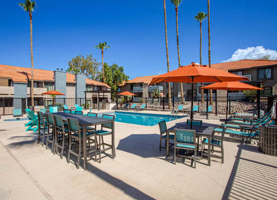A poolside area with tables and chairs and umbrellas.
