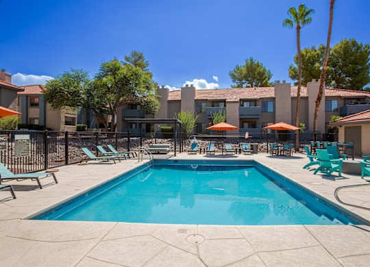 A swimming pool surrounded by lounge chairs and umbrellas.