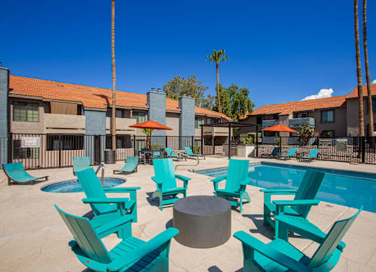 A pool area with blue chairs and a hot tub.
