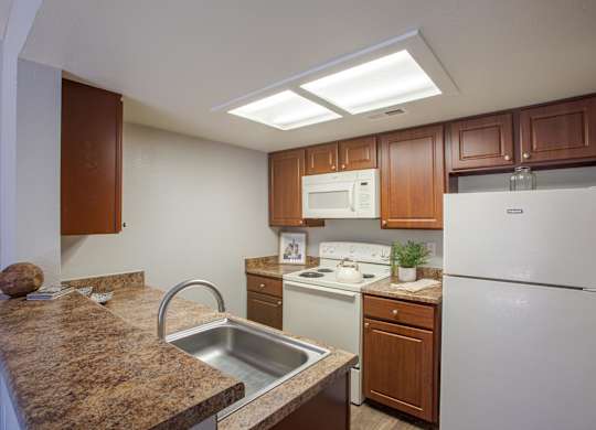 A kitchen with brown cabinets and a white refrigerator.
