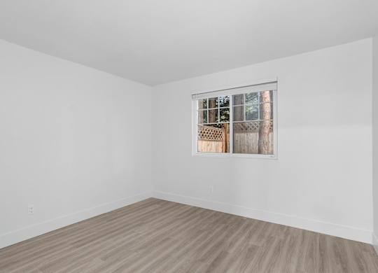 A room with a window and wooden flooring.