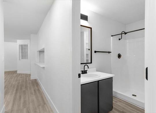 A bathroom with a sink, mirror, and shower.